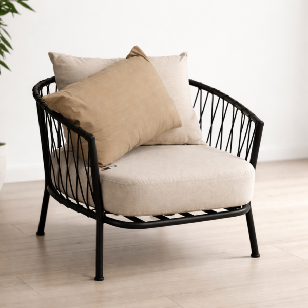 Sillón individual moderno con estructura metálica negra y almohadones beige en ambiente minimalista